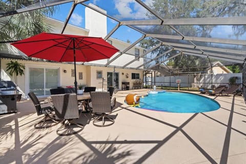 Step into your private oasis, a sparkling pool, comfy lounge seating under a bold red umbrella.
