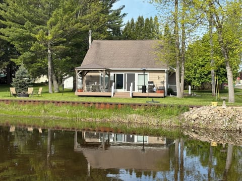 View of cottage from across the river. Riverside firepit on left. 
