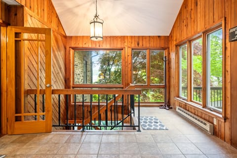 Natural light pours in through large windows framing the stone exterior, creating a cozy, sunlit transition space.