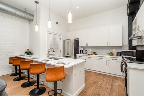 Unit 1: Fully equipped kitchen featuring stainless steel appliances, open counter space, and bar seating for 5 guests.