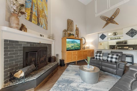 The living room features a wood burning fireplace, large smartTV, ample seating, and access to the private balcony.