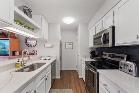 A full kitchen featuring stainless steel appliances, and breakfast bar seating 3.