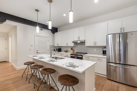 Unit 2: Kitchen with stainless steel appliances, white cabinetry and countertops, a central island, and breakfast bar seating for 4.