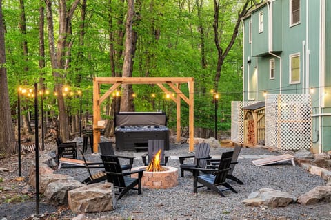 Gather by the fire under string lights and tall trees.