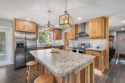 This cozy, bright, and welcoming kitchen with a large granite island, warm wood cabinets, and stainless steel appliances—perfect for cooking and gathering.