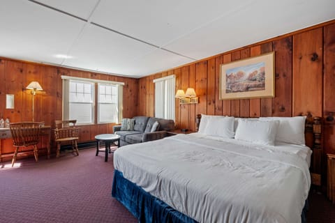 Welcome to your cozy King Room Retreat, featuring vintage pine paneling, a comfy bed with premium linens, a pull-out sofa bed, and modern comforts for a relaxing stay.