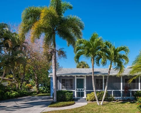Tucked among palm trees, this coastal home features a screened front porch and a private driveway.