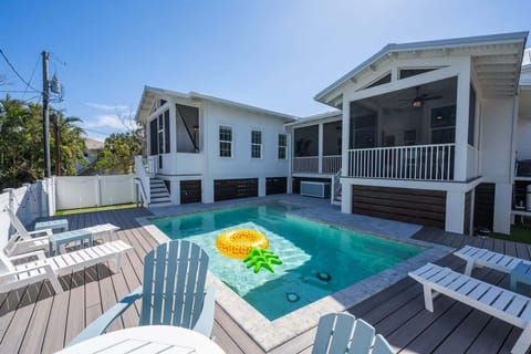 Private backyard with a pool, screened patio, and spacious sundeck. Features include lounge chairs, side tables, and Adirondack seating.