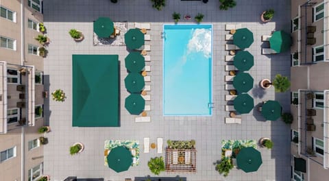 Aerial view of a pool with green umbrellas and lounge chairs