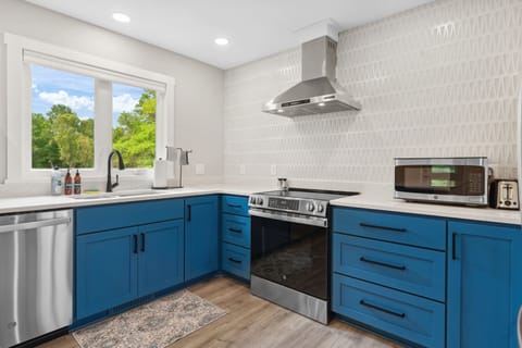 Cook with style in your modern kitchen featuring bold blue cabinets, stainless appliances, and abundant natural light from the garden window.