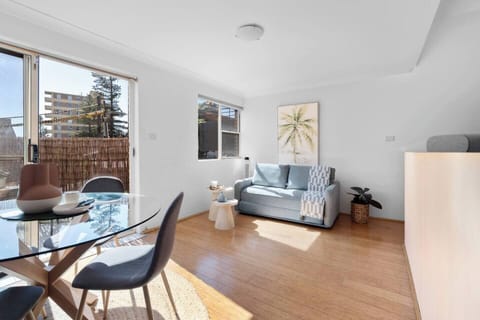 Step into the bright and welcoming living area where you can unwind on the sofa, enjoy shared meals at the glass dining table, and let the natural light and sea breeze pour in through the sliding doors.