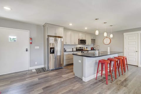 Fully equipped kitchen with stainless steel appliances, ample counter space, and vibrant bar seating for casual dining