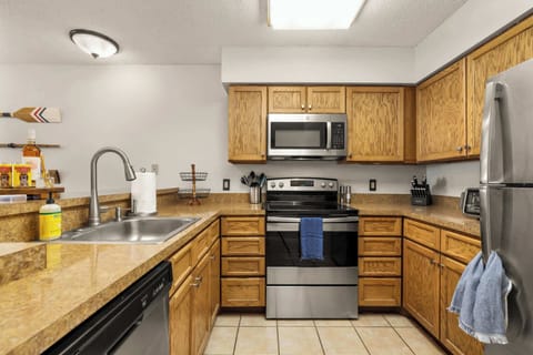 Fully stocked kitchen with bar seating, stainless steel appliances, and open layout.