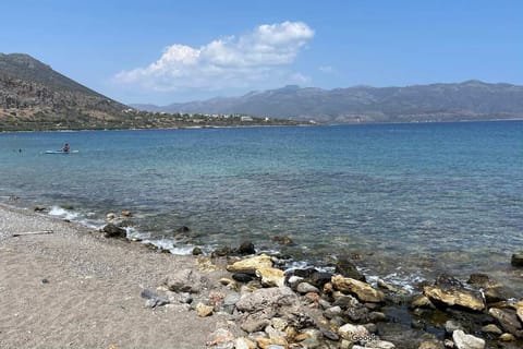 A serene pebbled beach with crystal-clear water, perfect for a refreshing swim.

