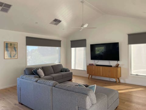 Large living room with high-ceilings, flat screen TV, fan and heating. 