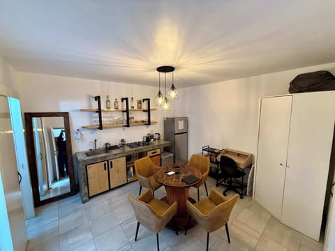 Sala (mesa con 4 sillas, escritorio individual con silla, lámpara de lectura, cocina integrada, espejo alto, clóset, barra con estufa integrada, tarja, repisas con tazas, copas y licores, refrigerador, stand con snacks, minibar)