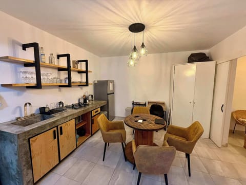 Sala (mesa con 4 sillas, escritorio individual con silla, lámpara de lectura, cocina integrada, espejo alto, clóset, barra con estufa integrada, tarja, repisas con tazas, copas y licores, refrigerador, stand con snacks, minibar)