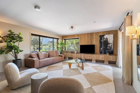 Living space with two plush sitting chairs, leather sofa, smart tv, coffee maker, wine/mini fridge, microwave and storage space.