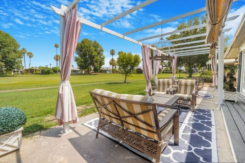 Outdoor lounge under pergola with seating and lush fairway views