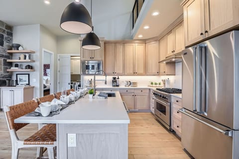 This luxury kitchen features a spacious center island with elegant seating, modern stainless steel appliances, and warm wood cabinetry. Stylish pendant lighting completes this inviting, gourmet space.