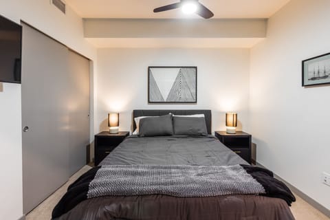 A cozy bedroom featuring a plush queen-sized bed, smart TV, and closet space