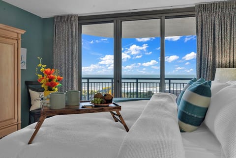 Sleep in Luxury: King-sized bed with new pillows and linens with a view of the ocean from the balcony. 