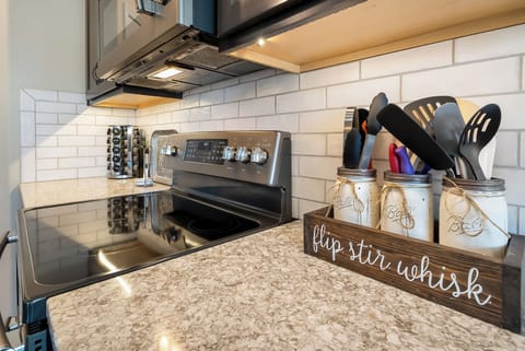 Your fully equipped kitchen invites culinary adventures with granite counters, modern appliances, and charming mason jar utensil holders.