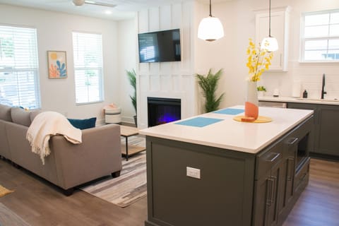 Relax in the bright and inviting living area, featuring a cozy fireplace and a spacious kitchen island perfect for gathering.