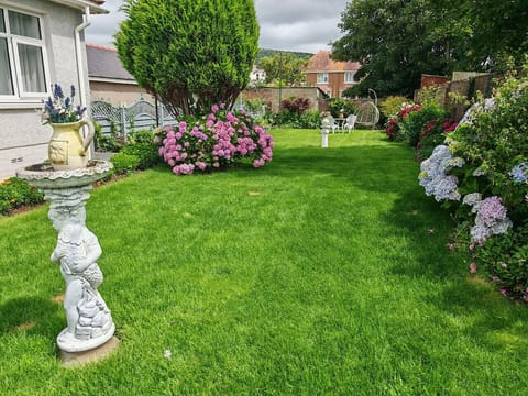 Enclosed garden lawn with planted borders and garden ornaments.