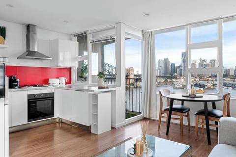 Prepare meals in the modern kitchen with a gas stove, a Nespresso machine and a pop of bold colour against the harbour backdrop.