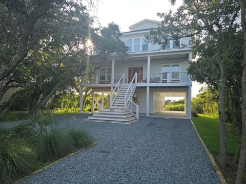 Charming Low Country beach home with wide front porch, custom trim, nestled among live oak trees.