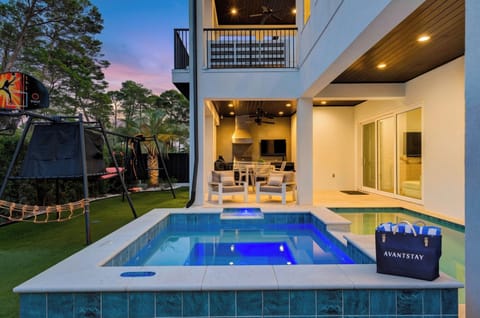 Sunset pool vibes with a covered lounge, outdoor TV, and dining area—your private backyard retreat for easy nights in. (The Coastal Clubhouse on 30A)
