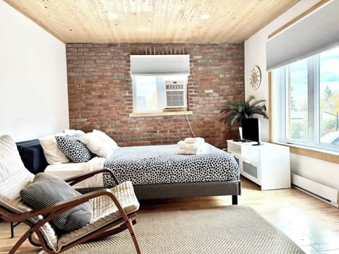 Chambre douillette : Profitez d’un lit Queen confortable et d’un matelas pliable Queen pour plus de flexibilité. La lumière naturelle, les murs de brique et le décor élégant créent une ambiance chaleureuse et accueillante.