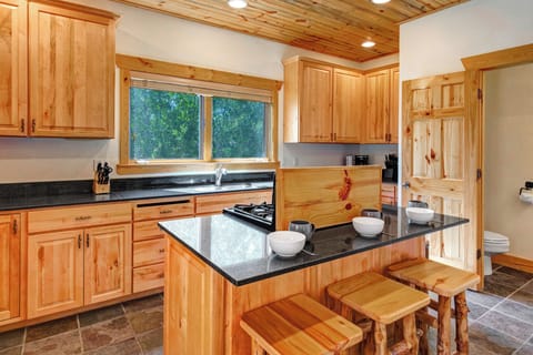 The well equipped kitchen has stainless appliances, black granite counters, and wood cabinets.