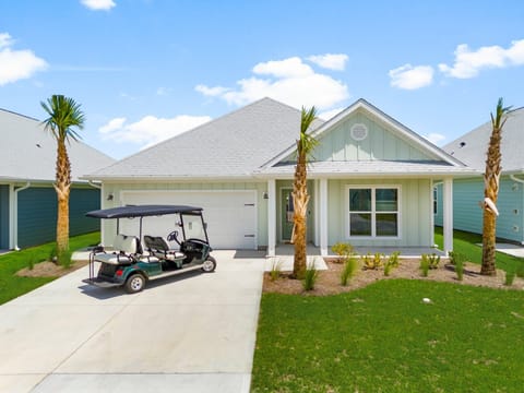 Modern coastal-style home with convenient golf cart access and tropical landscaping in a peaceful residential setting.