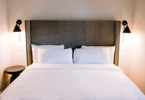 Drift off in a serene bed framed by warm bedside sconces.