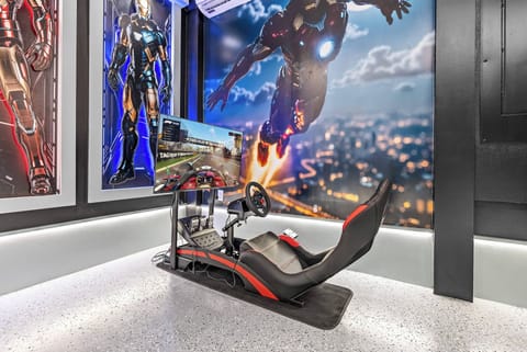 Enjoy the thrill in our gaming corner, complete with a racing simulator, a comfy seat, and a large screen. Vibrant wall art enhances the atmosphere, making it a perfect spot for entertainment and fun.
