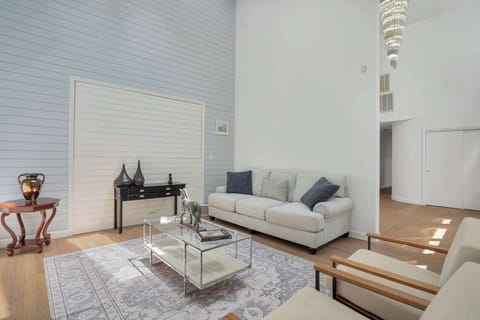 Sitting room with double-height ceiling, blue shiplap accent wall, and tiered chandelier