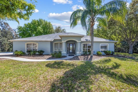 Single-story home with a welcoming entrance surrounded by mature trees and landscaping.