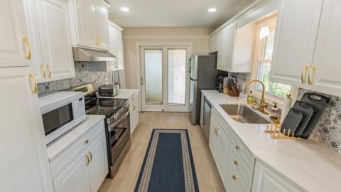 Kitchen is fully stocked with cookware, utensils, flatware and dishware.