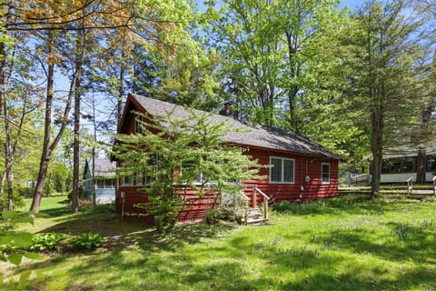 Charming exterior view of the red cabin nestled among mature trees, offering a peaceful and private retreat in nature.