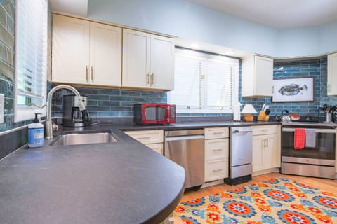 The kitchen features white cabinets, a tiled backsplash and stainless steel appliances.