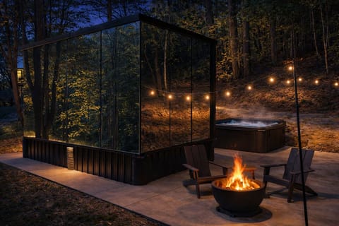 Twilight at Muir — where firelight, forest reflections, and a private hot tub set the tone for slow evenings in the woods.