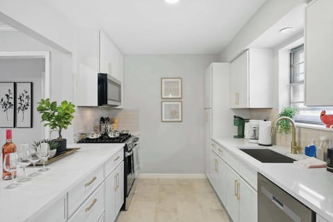 Featuring white cabinets, a breakfast bar with gold stools, and matching gold hardware and fixtures.