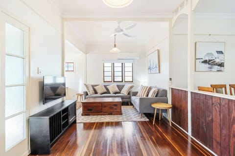Rest in the bright living area with plush seating, timber floors, a ceiling fan, and split-system air conditioning, perfect for kicking back after a day in the sun.