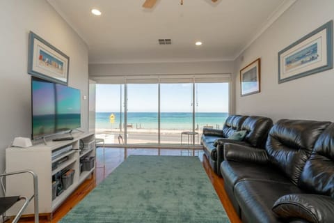 Unwind in the living area where a comfortable three-seater and two-seater sofa face the TV, while large windows frame uninterrupted Brighton Beach views and air conditioning keeps the space comfortable year-round as you relax with puzzles, board games, or