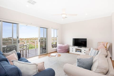 Unwind in the sunlit upstairs living area, where coastal light and dune views invite slow mornings or lazy evenings in.