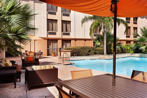 Lounge poolside with shaded seating and refreshing blue water.