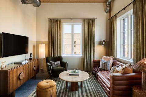 TV lounge with brown sofa, round table, and sunny window view
