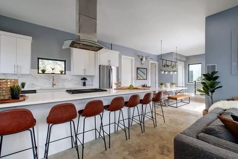 The open-concept kitchen features sleek amenities and a 7-person bar for seating.